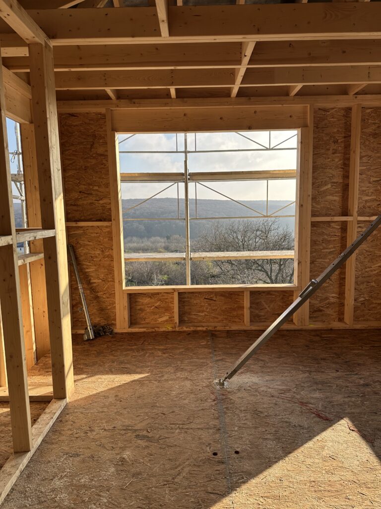 Unfinished timber frame room with large framed window opening before window installation