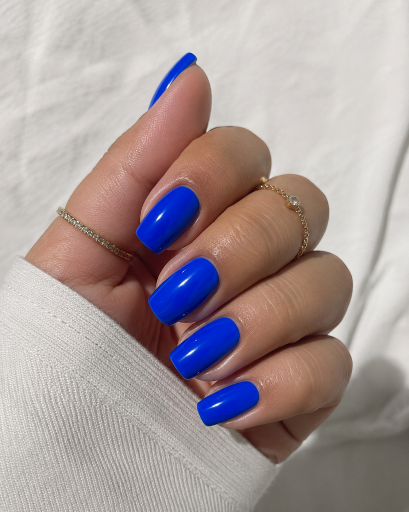 Electric cobalt blue nails on coffin shaped gel manicure with gold rings