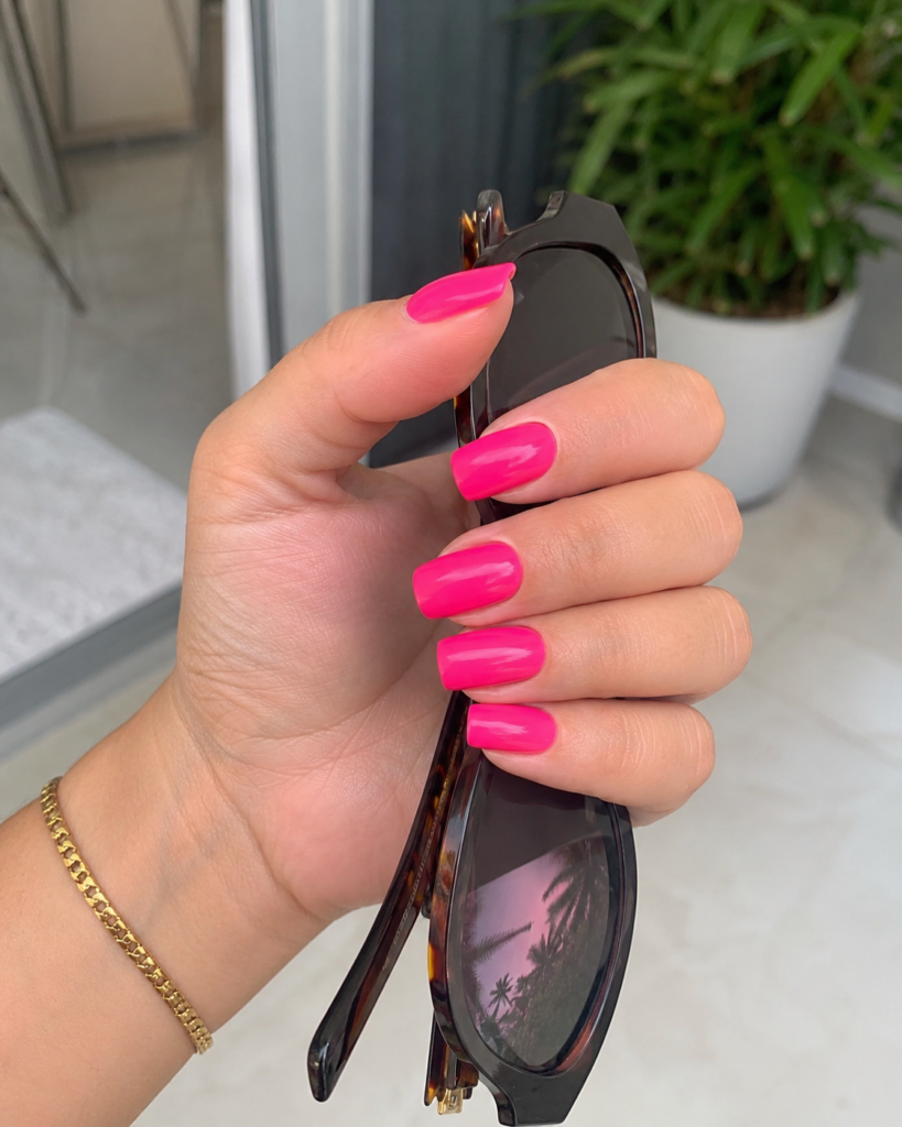 Vibrant hot pink glossy nails on coffin shaped gel manicure