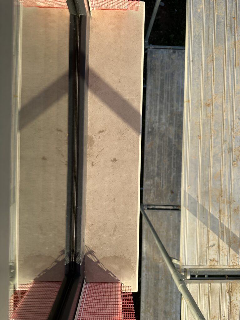 Top-down view of installed limestone exterior window sill showing stone surface detail and corner joint with window frame