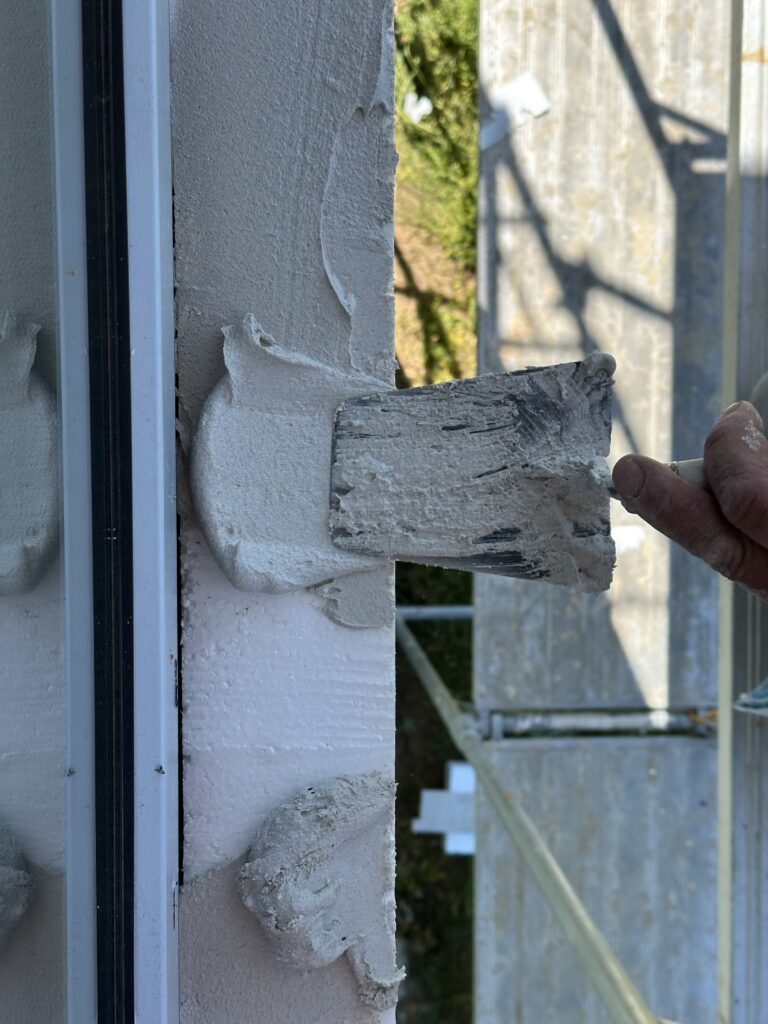 Applying mortar adhesive to insulation before installing limestone exterior window sill