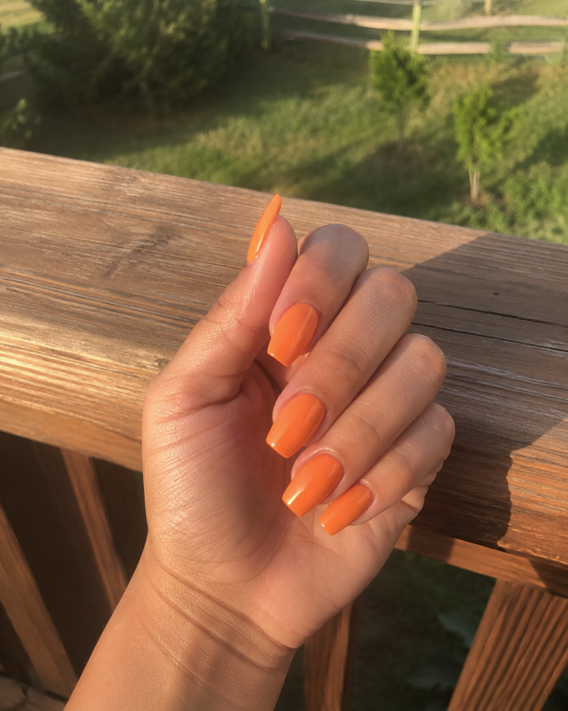 Warm sunset orange nails on coffin shaped gel manicure