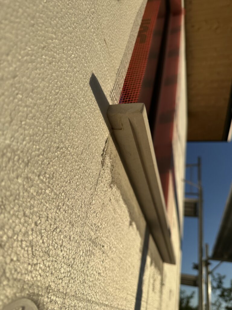 Drip edge detail on limestone window sill viewed from below showing the groove cut into the underside of the stone over EPS insulation