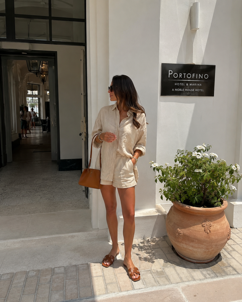 Beige linen matching set styled with brown sandals and a leather bag outside a bright hotel entrance.