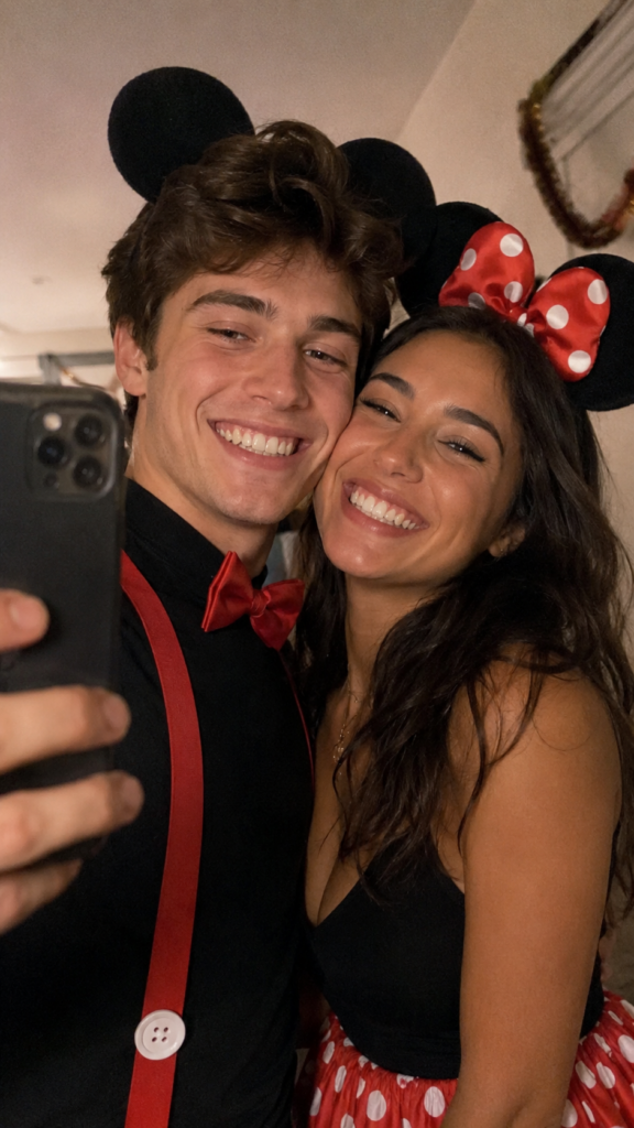 Couple in matching red, black, and white outfits with round mouse ears taking a selfie, Mickey and Minnie Disney Halloween costume