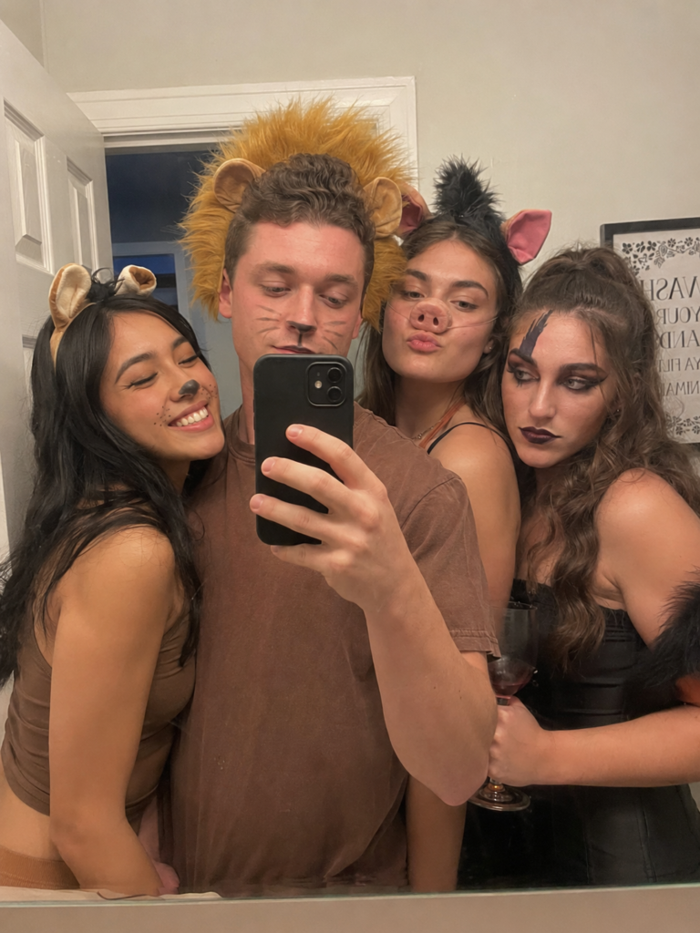 Friends in earth-toned animal costumes with face paint taking a mirror selfie, Lion King Disney Halloween costume