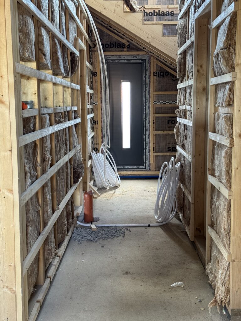 The re-routed orange canalization pipe running across the insulated ceiling and down the wall, which will be boxed in as a decorative third beam