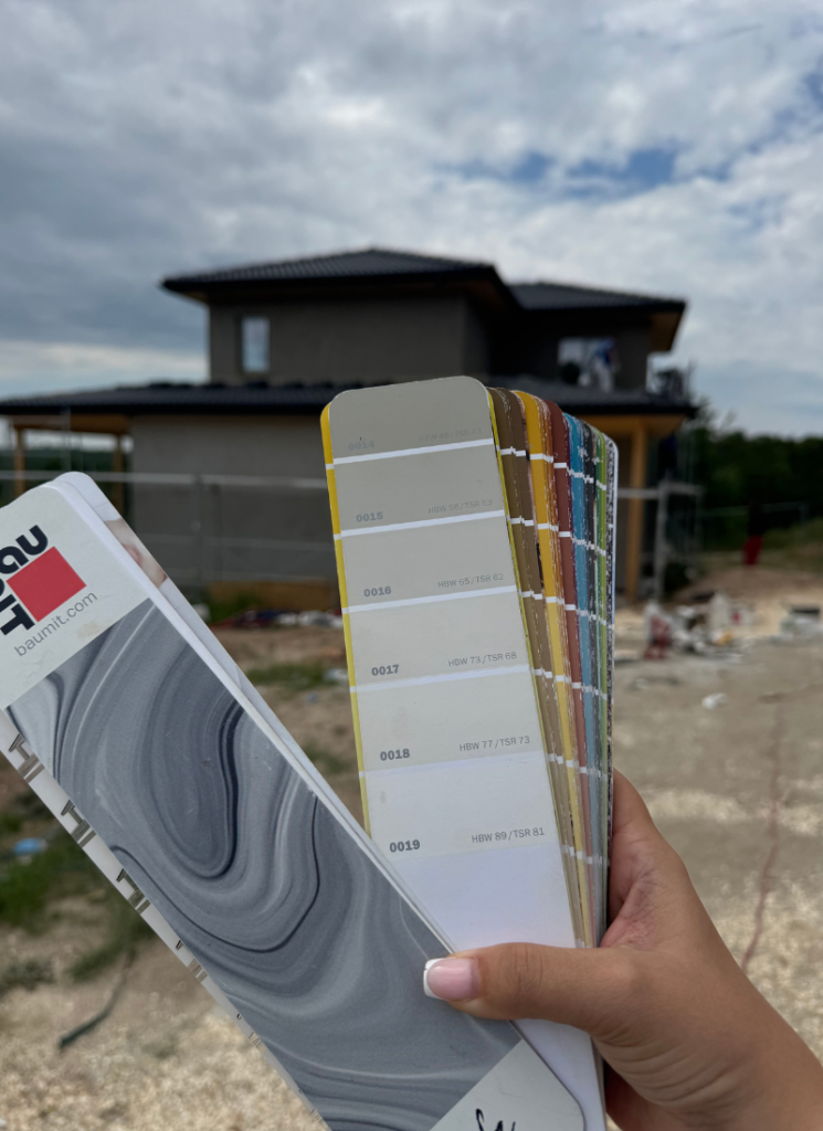 Baumit fan deck showing warm white exterior color options in front of the house