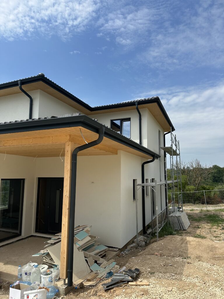 Warm white exterior house with natural wood soffits, black gutters, and black windows