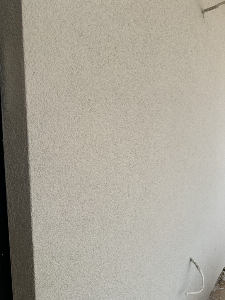 Close-up of 1.5mm warm white stucco texture on the finished exterior wall