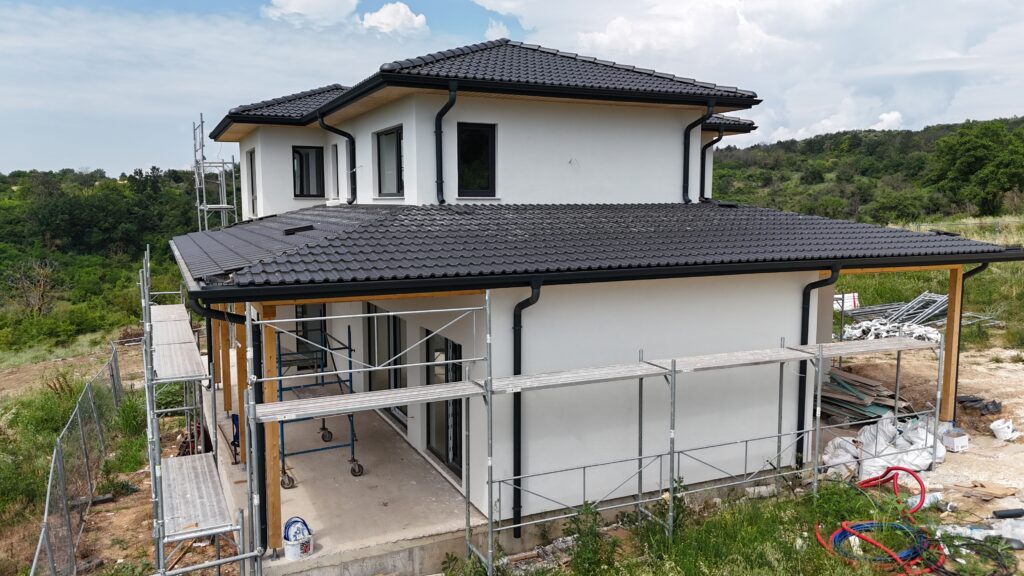 Warm white exterior on a modern house with black roof, wood soffits, and natural landscape views