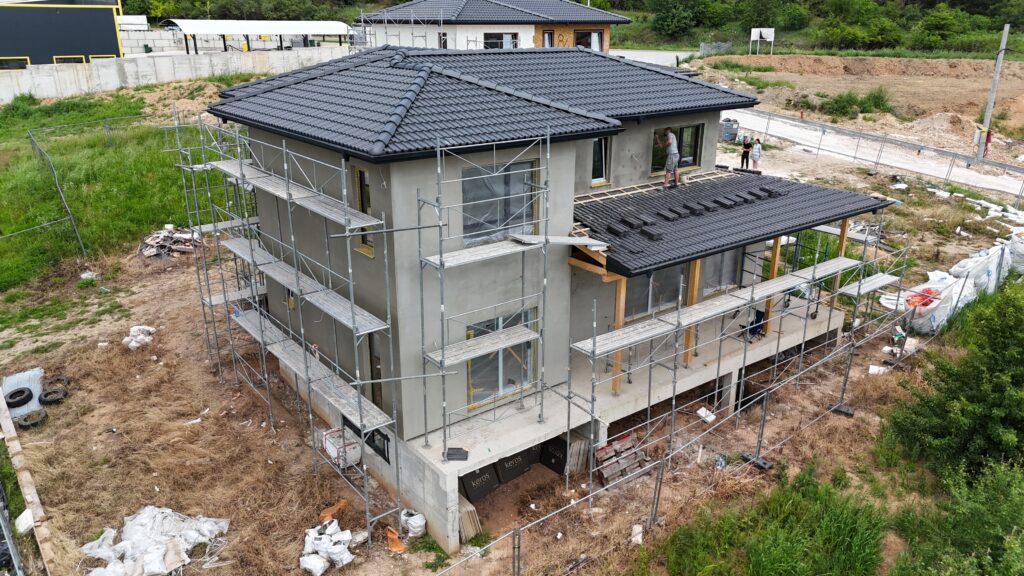 Grey base coat on house exterior before the final warm white stucco finish