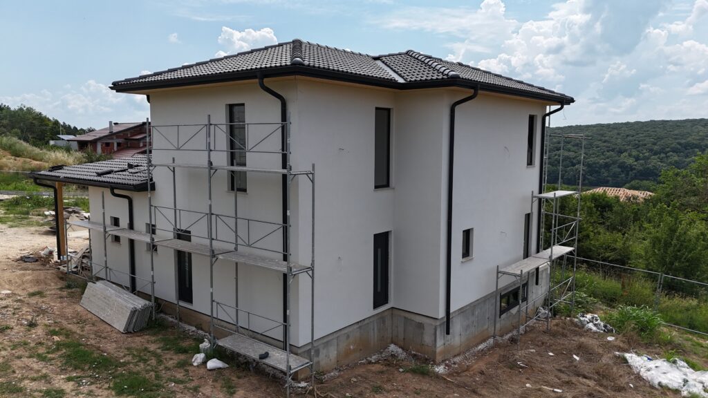 Finished warm white exterior house color with black windows and dark roof tiles